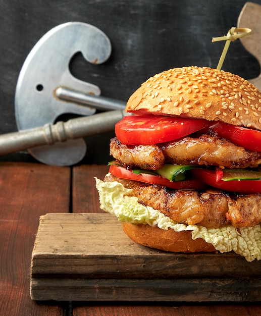 Hamburger avec steak frit au porc, tomates rouges, petit pain frais aux graines de sésame