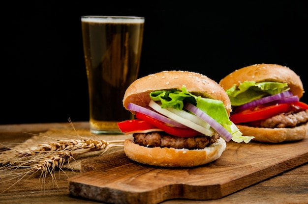 Photo hamburger avec une tasse de bière sur la table en bois