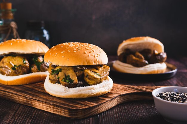 Des hamburgers appétissants avec des champignons grillés et des herbes sur une planche de bois