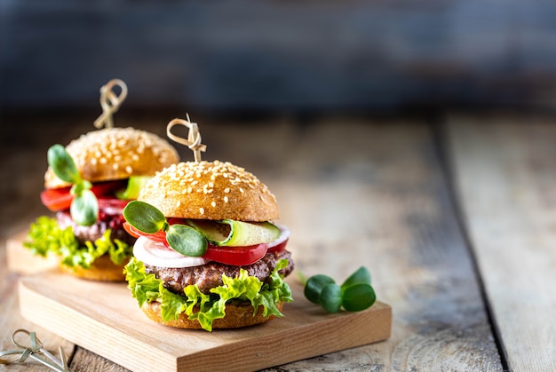 Hamburgers faits maison avec escalope, laitue fraîche, tomates, oignons sur une table en bois. copie espace