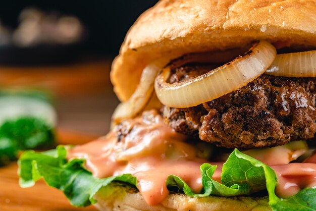 Hamburgers faits maison grillés frais avec du fromage d'oeuf au plat de tomate de boeuf et de la laitue sur le fond en bois