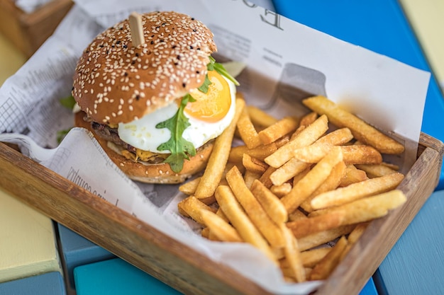 Hamburgers et frites sur le plateau en bois. Hamburger de boeuf gastronomique avec laitue et fromage frit