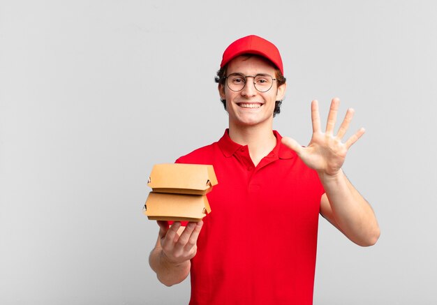 Les hamburgers livrent un garçon souriant et amical, montrant le numéro cinq ou cinquième avec la main en avant, comptant à rebours