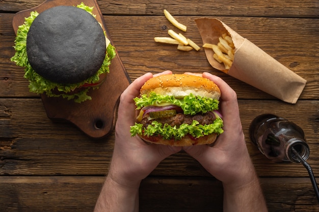 Des hamburgers savoureux frais avec des frites, boire sur la vue de dessus de table en bois.