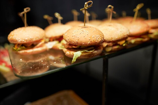 Hamburgers sur un support en verre Stand en verre avec de nombreux hamburgers Table de brunch avec des hamburgers