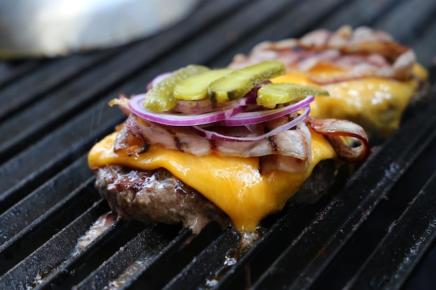 Hamburguer Hamburger brésilien grillé sur parrilla avec fromage fondu bacon oignon rouge et cornichons