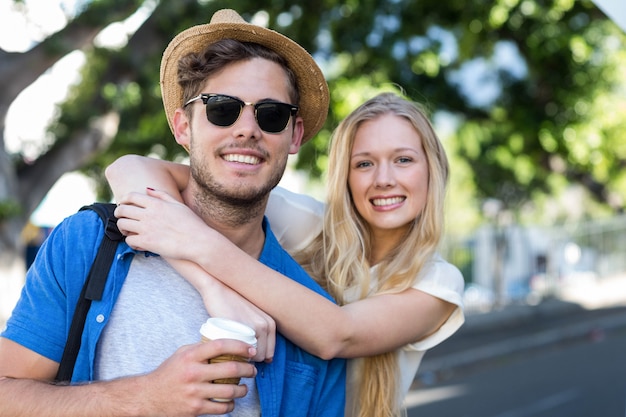 Hanche couple embrassant et souriant à la caméra à l&#39;extérieur