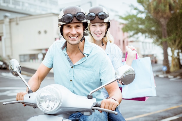 Hanche jeune couple équitation scooter avec des sacs à provisions