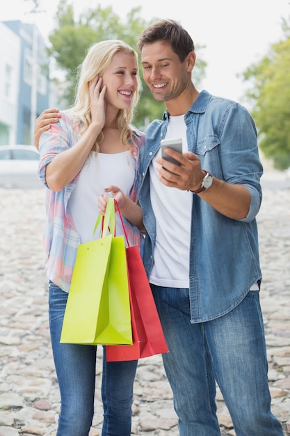 Hanche jeune couple regardant smartphone sur le voyage de shopping