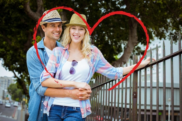 Hanche jeune couple souriant à la caméra par des garde-corps contre le coeur