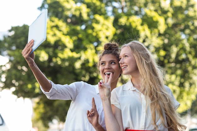 Hanches amis prenant des selfies avec tablette dans les rues