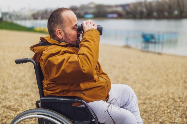 Un handicapé paraplégique en fauteuil roulant utilise des jumelles en plein air