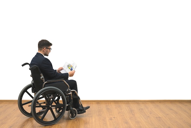 Les handicapés dans un fauteuil roulant tenant des papiers sur le fond du mur blanc