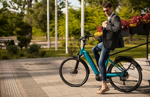 Handosme jeune homme d'affaires sur le vélo électrique dans la rue