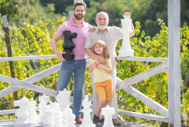 Happt grand-père père et fils jouant aux échecs Hommes de différents âges jouant au jeu d'échecs Trois