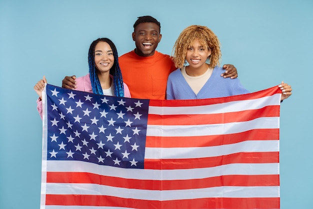 Photo happy african american friends holding american flag looking at camera isolated