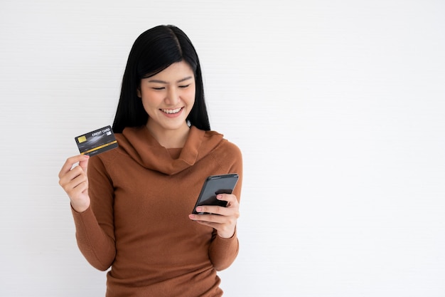 Happy Asian woman holding carte de crédit et smartphone pour les services bancaires mobiles sur internet.