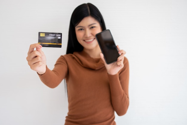 Happy Asian woman holding carte de crédit et smartphone