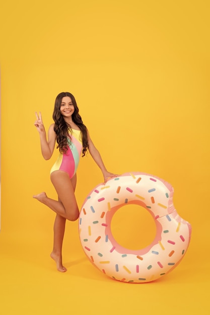 Happy beach kid en maillot de bain avec anneau gonflable beignet sur maillot de bain fond jaune