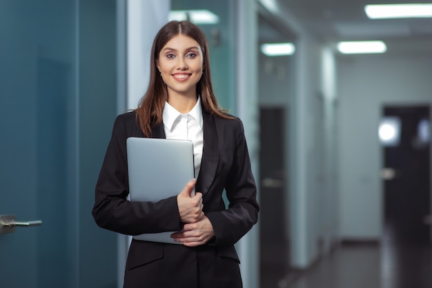 Happy Beautiful Business Woman in Office Hall avec un ordinateur portable