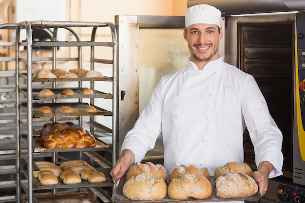 Happy boulanger montrant un plateau de pain frais