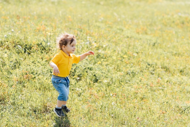 Happy boy court et joue à l'extérieur dans un champ