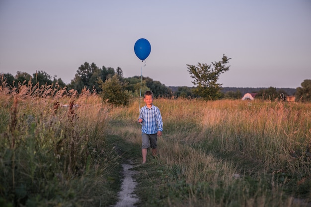 Happy Boy fait ses vœux et ses rêves à l'extérieur avec un ballon Belle liberté de carte d'été