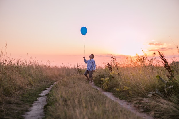 Happy Boy fait ses vœux et ses rêves à l'extérieur avec un ballon Belle liberté de carte d'été