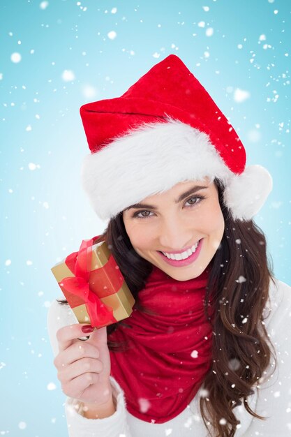 Happy brunette holding christmas gift contre fond bleu avec vignette