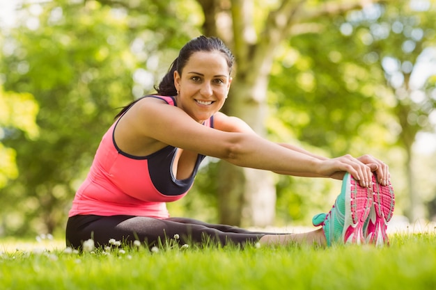 Happy brunette en sportswear qui s&#39;étend sur l&#39;herbe