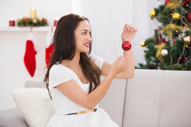 Happy brunette tenant une boule rouge à noël