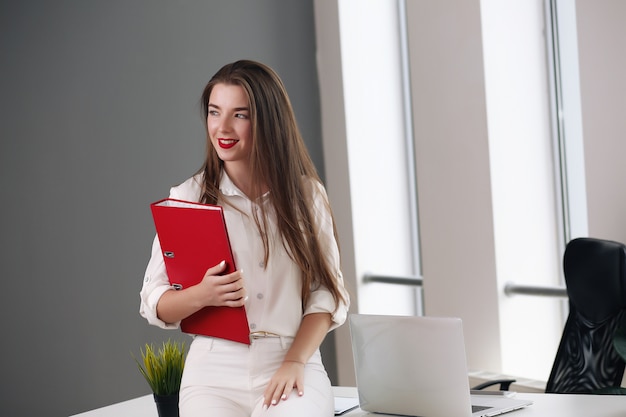 Happy businesswoman leaning on desk in office, office europe