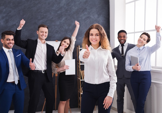 Happy businesswoman with multiracial team showing Thumbs up in office