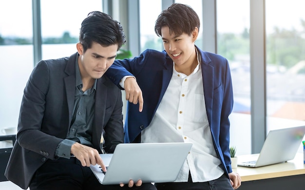 Happy Company Jeune homme d'affaires asiatique et coaching secrétaire personnel assistant garçon manqué partenaires lesbiennes et LGBT tout en travaillant avec un ordinateur portable et une stratégie dans les affaires au bureau