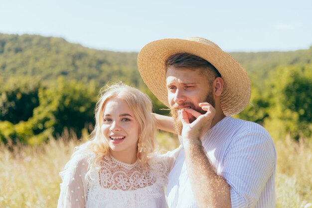 Happy country guy dans un chapeau se tient avec sa petite amie bien-aimée en été par une journée ensoleillée