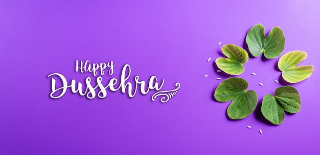 Happy Dussehra avec des feuilles vertes sur une surface violette