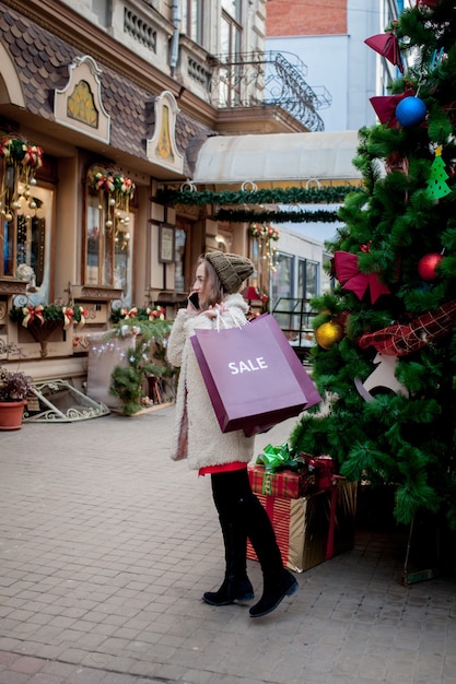 Happy girl détient des sacs en papier avec le symbole de la vente dans les magasins avec des ventes à Noël