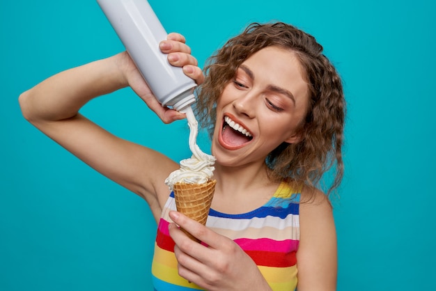 Happy girl holding wafer cone et application de crème, souriant.