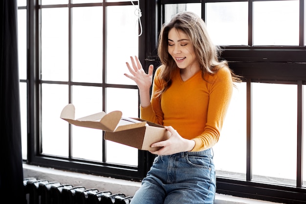 Happy girl ouvre une boîte de corton à la maison, livraison, courrier et concept de personnes