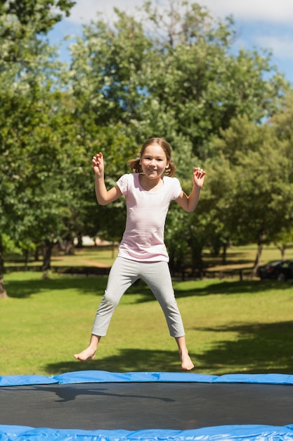 Happy girl sautant haut sur le trampoline dans le parc