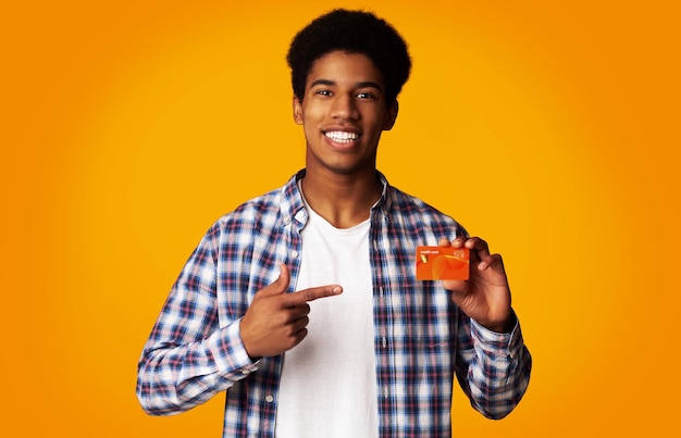 Photo happy guy holding carte de crédit et pointez dessus