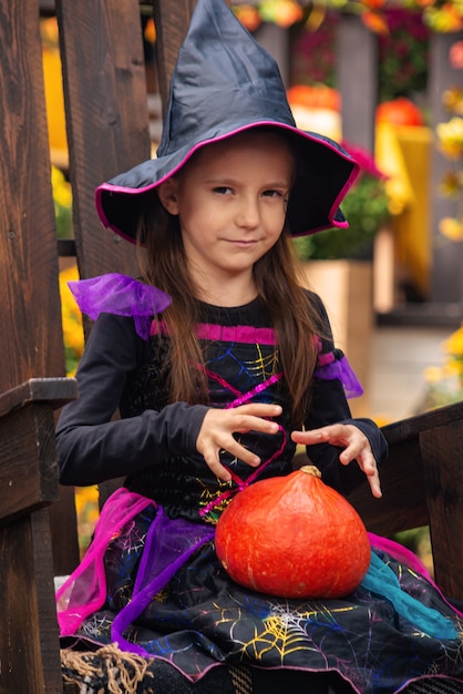 Happy Halloween Petite sorcière mignonne avec une citrouille dans les mains