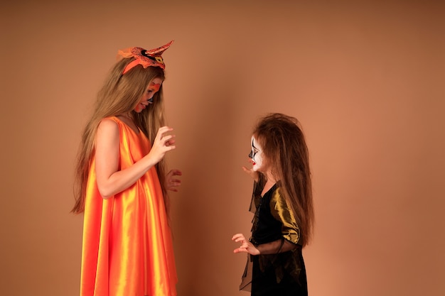 Happy Halloween portrait d'enfants en costumes sur un mur beige