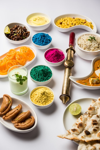 Photo happy holy concept montrant des plats indiens pour le déjeuner comme le beurre de paneer masala naan jeera riz noir chana fry jalebi ras malai thandai et farsan avec des couleurs holi et pichkari