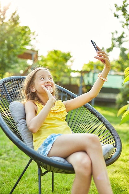 Happy kid girl holding smartphone ayant un appel vidéo avec un ami à distance