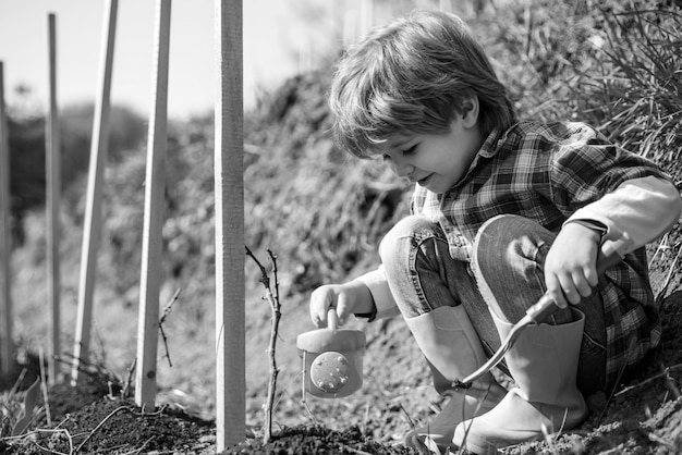 Happy Kid avec pelle et arrosoir Arroser les fleurs dans le jardin