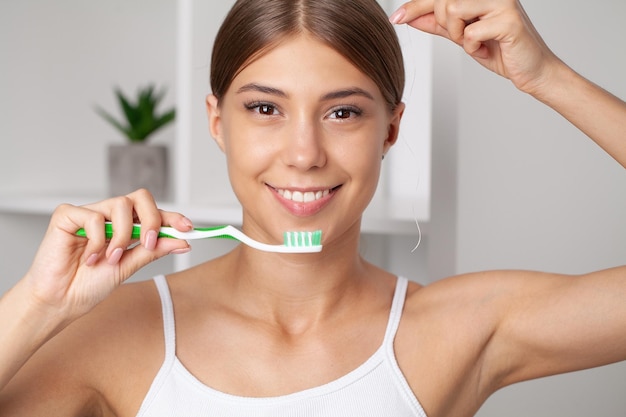 Happy Lady se brosser les dents avec une brosse à dents debout dans la salle de bains