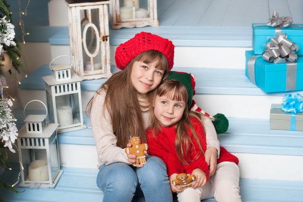 Happy little sisters hugging on porche à la maison à Noël