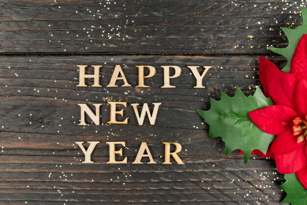 Photo happy new year 2023 celebration wooden text and poinsettia on wooden background flat lay