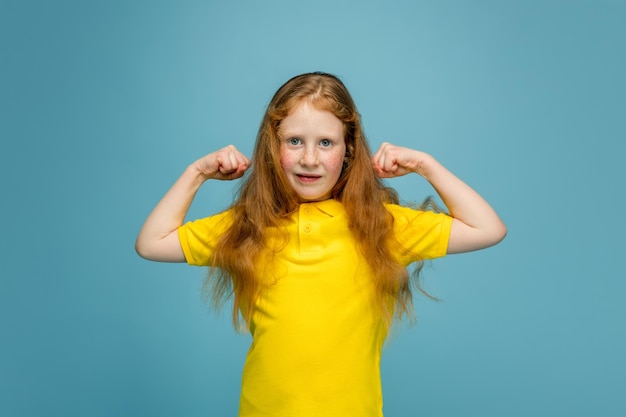 Happy redhair girl isolated on blue studio background Semble heureux joyeux sincère Copyspace Éducation de l'enfance concept d'émotions